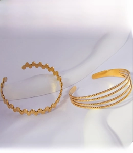 Detail view of gold-plated geometric open bangles with high-shine PVD coating