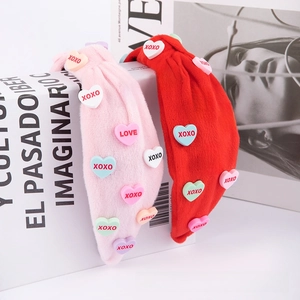 Detail of red and pink velvet knotted headband with colorful XOXO heart patches decoration