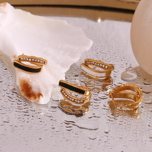Detail view of 18K gold plated hoop earrings with black white enamel and zircon accents