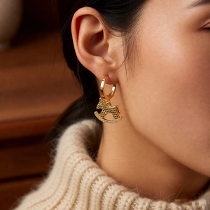 Détail de boucles d'oreilles cheval à bascule plaquées or 18 carats portées à l'oreille