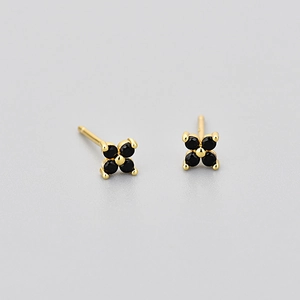 Close-up of four-petal flower stud earrings with black stones and gold-tone base