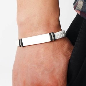 Close-up of a white braided leather bracelet featuring a polished silver metal plate