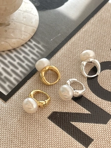 Detailed view of baroque pearl earrings in gold and silver finish on a fabric background