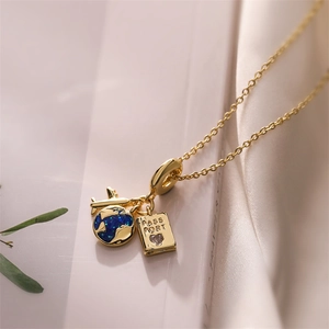 Details einer Goldkette mit Flugzeug, blauem Globus und Reisepass Anhängern