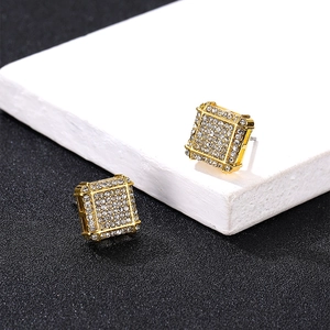 Close-up of gold square stud earrings with pave-set diamonds on a marble background