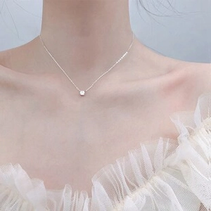 Primo piano di una catenina d'argento con una piccola pietra di zircone su una modella