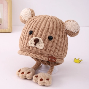 Detail der Bären-Ohrenklappenmütze mit grober Strickstruktur und flauschigen Bärenpfoten