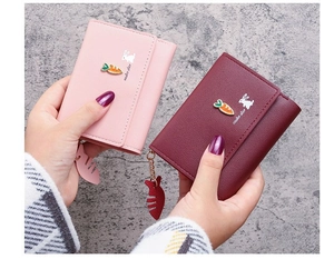 Close-up of pink and burgundy tri-fold wallets with cute rabbit prints and fish charms