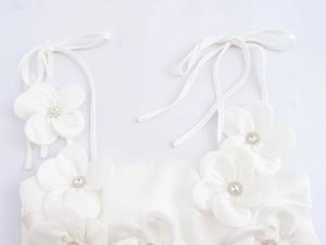 Detail von 3D-Stoffblumen mit Strasssteinen auf einem weißen Satin-Top