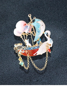 Detailed close-up of a sailboat and swan brooch with enamel finish and gold tassels