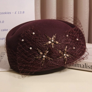 Detail of burgundy wool pillbox hat with elegant mesh veil and pearl star embroidery