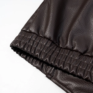 Dettaglio della giacca in pelle marrone scuro con polsino elastico e texture di qualità