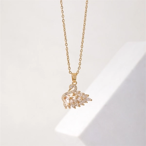 Elegant gold swan pendant necklace with sparkling cubic zirconia on a white geometric stand