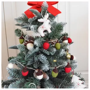 Detail von Wollfilz-Eichelgirlande und Rentier-Ornament an einem verschneiten Weihnachtsbaum