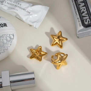 Detailed view of gold star earrings and ring set styled with lifestyle lifestyle accessories