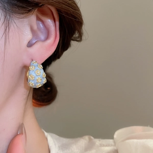 Macro detail of French vintage C-shape enamel flower earring with gold floral pattern