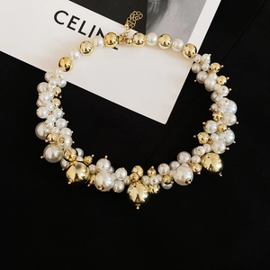 Detailed close-up of French irregular beaded pearl necklace with gold metallic spheres