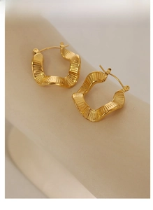 Close-up of 18K gold irregular wavy earrings with textured matte finish on display