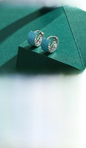 Macro detail of silver rectangular hoop earrings featuring pavé-set blue turquoise stones
