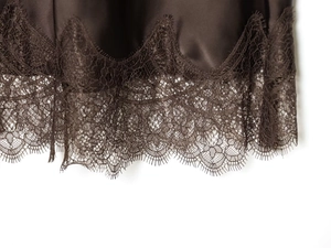 Détail d'une jupe midi en satin chocolat avec bordure délicate en dentelle de cils au bas