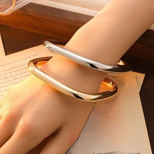 Minimalist gold and silver metallic bangles shown on wrist in an elegant lifestyle scene