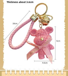 Detail view of pink knit-texture bear keychain with size dimensions and gold bell charm