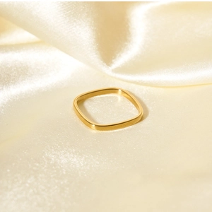 Minimalist square gold ring displayed on elegant cream silk fabric texture