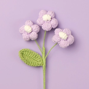 Handmade crochet bouquet with three purple puff flowers on a soft violet background