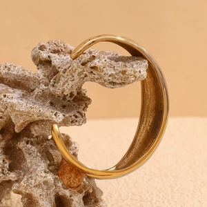 Detailed close-up of a two-tone 18K gold plated bangle on a textured stone surface