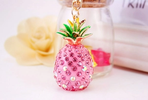 Close-up of pink rhinestone pineapple keychain with golden lobster clasp and green leaf