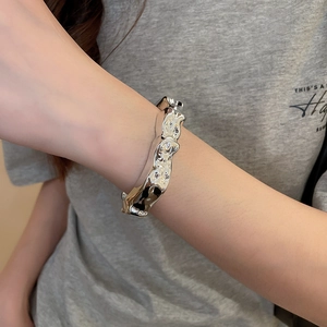Detailed view of silver cuff bracelet with irregular lava texture and metallic finish