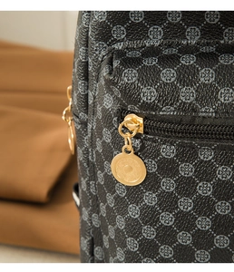 Detailed macro view of black textured leather bag with gold zipper and heart pattern