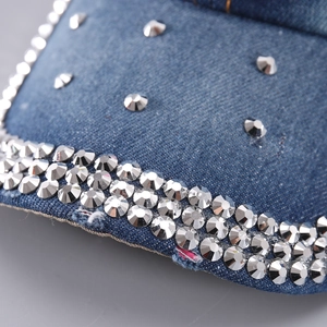 Macro des strass argentés sertis main sur le bord en denim bleu de la casquette
