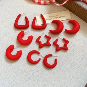 Red matte acrylic geometric star and crescent hoop earrings set on fabric background