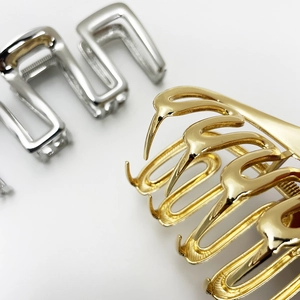 Detail shot of hollow wavy hair claws in metallic gold and silver finish for women