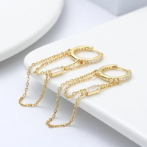 Macro detail of gold-plated silver chain drop earrings featuring rectangular zircon stones