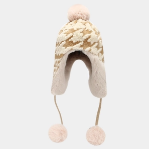 Close-up of houndstooth knit trapper hat featuring faux fur lining and pink pom-poms