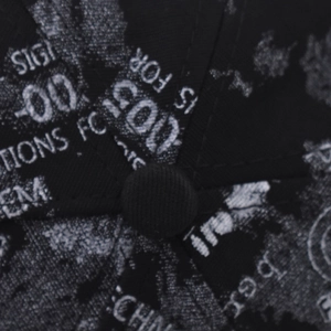 Macro shot of graffiti print patterns and stitching details on a black hip hop cap