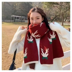 Red Christmas knit scarf with white elk patterns and green bow ties worn on grass