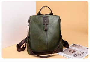 Detail of vintage green PU leather backpack with brown trim and metal zipper pocket