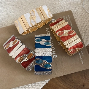 Detail of four colorful enamel stretch bracelets with metallic hammered texture and gold finish