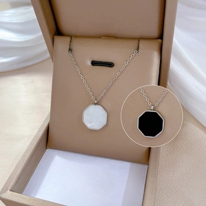 Macro view of titanium steel necklace pendants in white shell and black onyx on silk