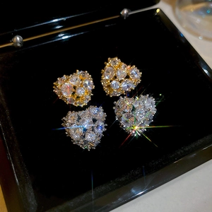 Detailed view of heart-shaped studs featuring gold and silver settings with sparkling zircons