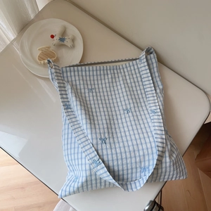 Detail shot of blue gingham cotton tote bag featuring delicate butterfly embroidery