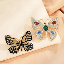 Detailed shot of emerald and multicolor rhinestone butterfly brooches on silk fabric