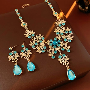 Macro view of vintage gold necklace and blue crystal teardrop pendant jewelry set