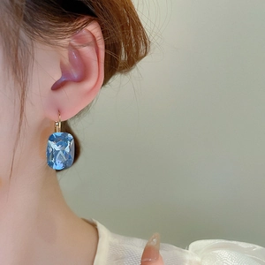 Close-up of model wearing sea-blue crystal earrings with gold finish in French style