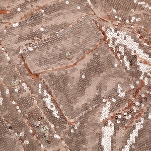 Close-up of rose gold sequin fabric featuring a pocket with a silver metal snap button