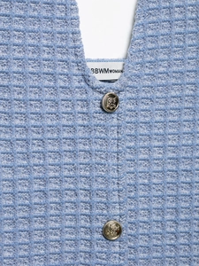 Detail of light blue waffle knit fabric with vintage embossed gold metal buttons