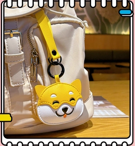 Close-up of a cute yellow Shiba Inu plush keychain hanging on a beige canvas backpack